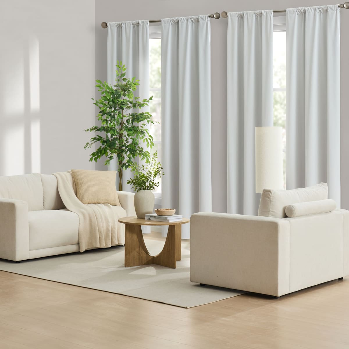 White Contractor Set panels on rods at two tall windows in a bright, sparsely furnished room